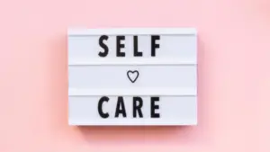 sign on a pink background that say self care